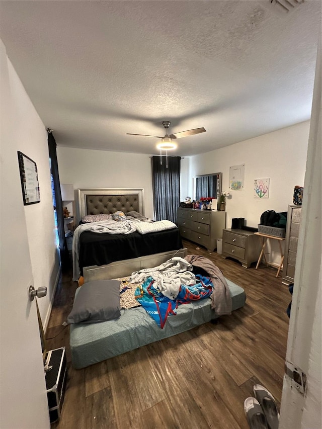 bedroom featuring dark hardwood / wood-style flooring, ceiling fan, and a textured ceiling