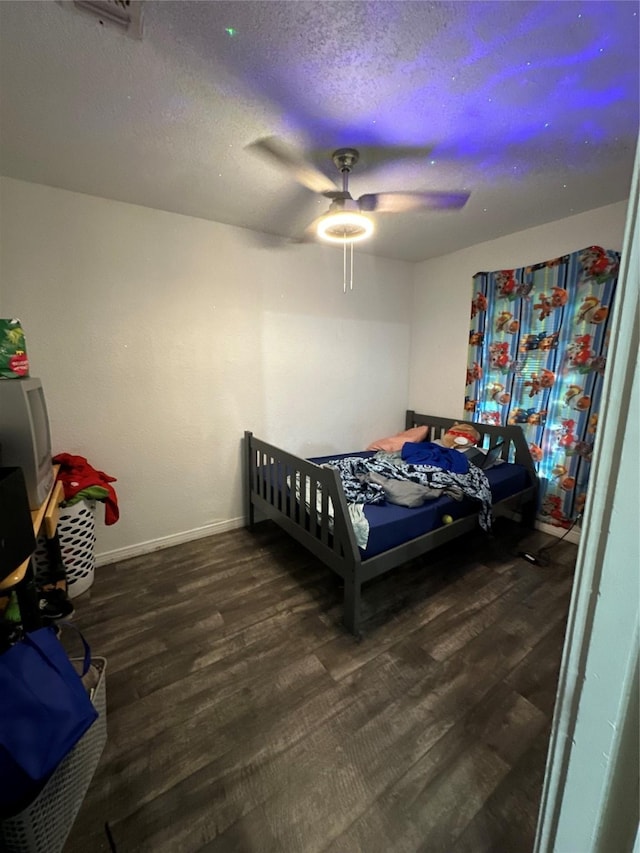 bedroom with ceiling fan, dark wood-type flooring, and a textured ceiling