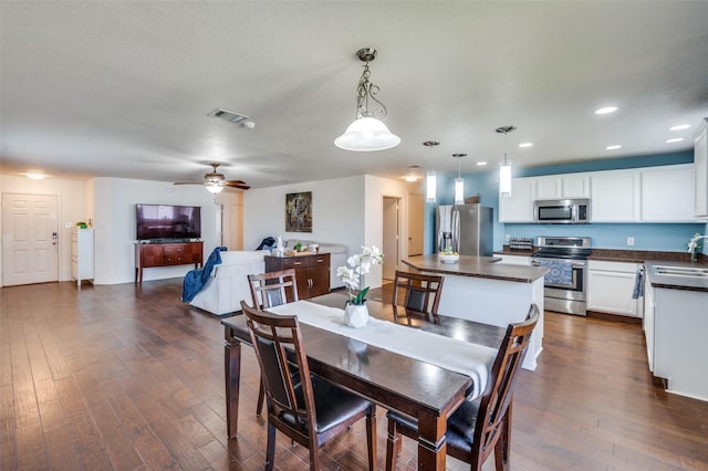 dining room with sink, dark wood-type flooring, a textured ceiling, and ceiling fan