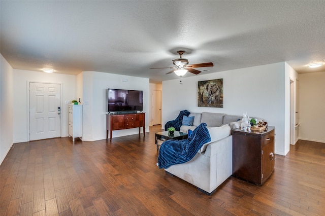 living room with dark hardwood / wood-style flooring, ceiling fan, and a textured ceiling