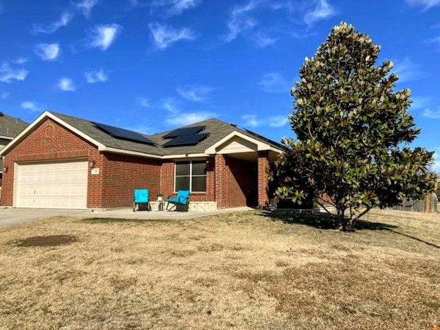 view of front facade featuring a garage, a front yard, and solar panels