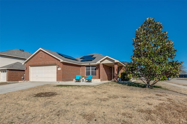 ranch-style home with a garage, a front lawn, and solar panels