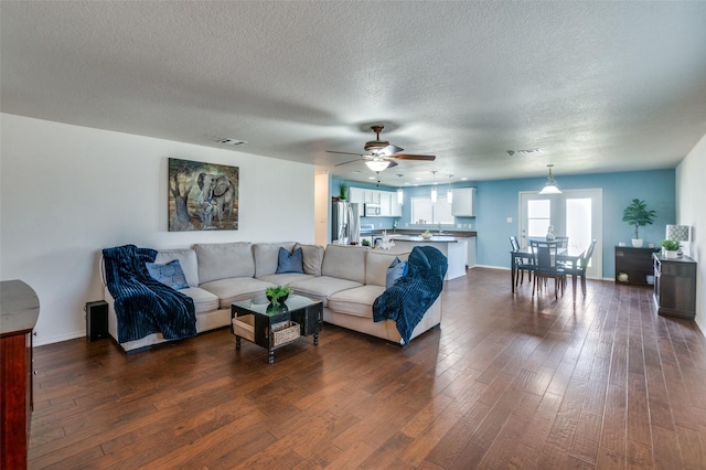 living room featuring ceiling fan, dark hardwood / wood-style flooring, sink, and a textured ceiling