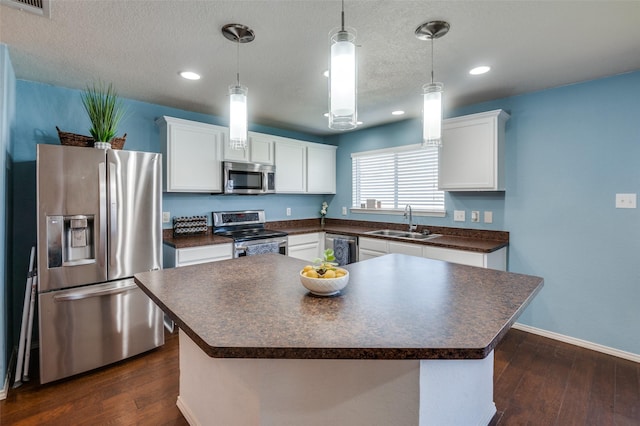 kitchen featuring pendant lighting, sink, stainless steel appliances, a center island, and white cabinets