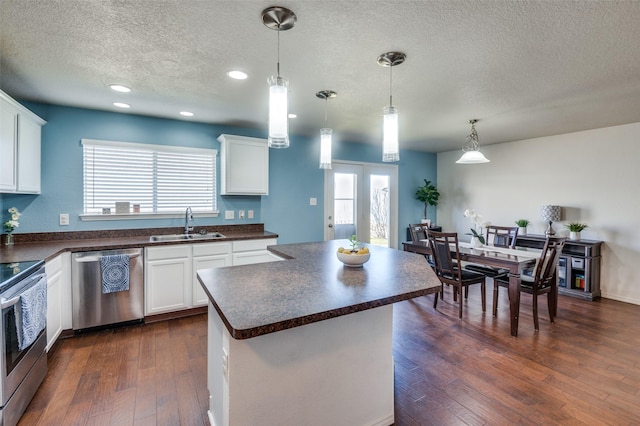 kitchen featuring stainless steel appliances, a kitchen island, white cabinets, and decorative light fixtures