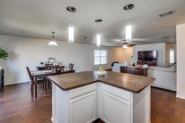 kitchen with white cabinetry, a center island, and dark wood-type flooring