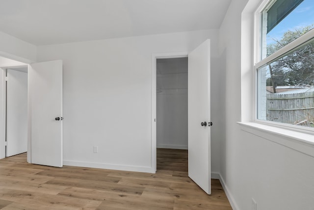 unfurnished bedroom featuring a walk in closet, light hardwood / wood-style floors, and a closet