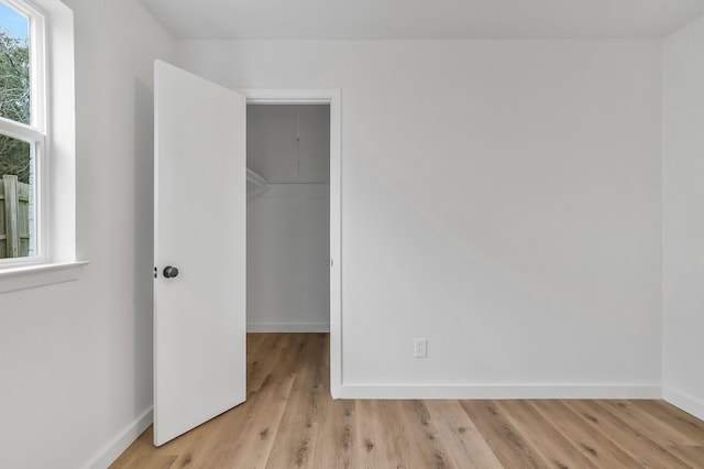 unfurnished bedroom featuring a closet, a spacious closet, and light hardwood / wood-style flooring