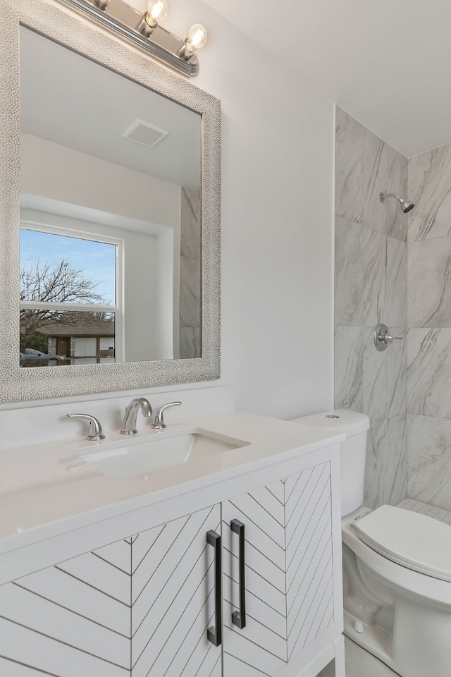 bathroom featuring vanity, toilet, and a tile shower