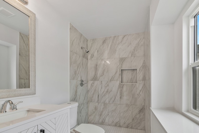 bathroom with vanity, toilet, and a tile shower