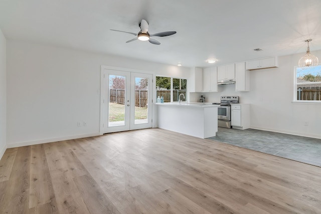 kitchen with electric stove, pendant lighting, a wealth of natural light, white cabinets, and french doors