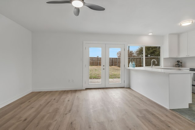 kitchen with white cabinetry, range, french doors, and light wood-type flooring