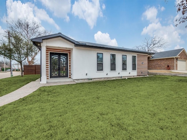 view of front of home featuring solar panels, a front lawn, and french doors