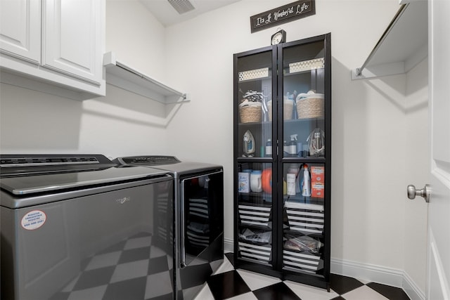 clothes washing area with cabinets and washing machine and clothes dryer