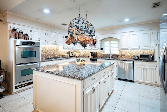 kitchen featuring white cabinetry, appliances with stainless steel finishes, dark stone countertops, and a kitchen island