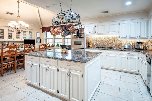 kitchen featuring a kitchen island, pendant lighting, white cabinets, and dark stone counters