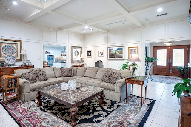 living room with beam ceiling, a towering ceiling, coffered ceiling, light tile patterned flooring, and french doors