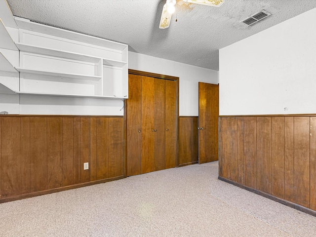 carpeted empty room with a textured ceiling and wood walls