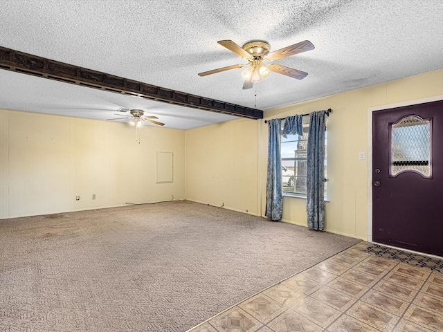 entryway with a textured ceiling, wooden walls, beamed ceiling, ceiling fan, and carpet