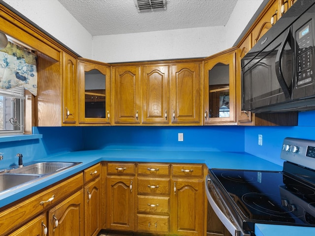 kitchen with stainless steel electric stove, sink, and a textured ceiling