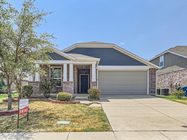 view of front of home featuring a garage, central AC unit, and a front yard