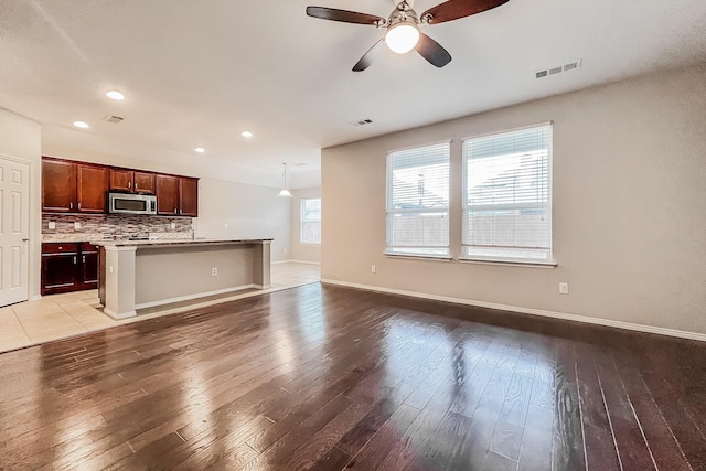 unfurnished living room with hardwood / wood-style flooring and ceiling fan