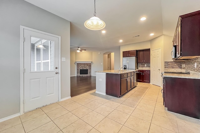 kitchen featuring a kitchen island, appliances with stainless steel finishes, pendant lighting, backsplash, and light tile patterned floors