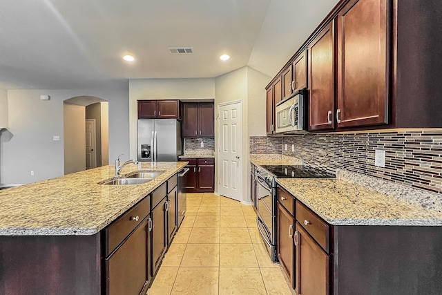 kitchen featuring sink, light tile patterned floors, stainless steel appliances, a kitchen island with sink, and decorative backsplash