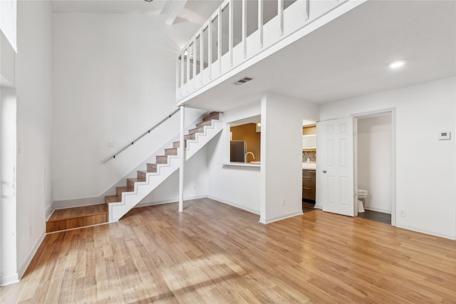 unfurnished living room with hardwood / wood-style flooring and a towering ceiling