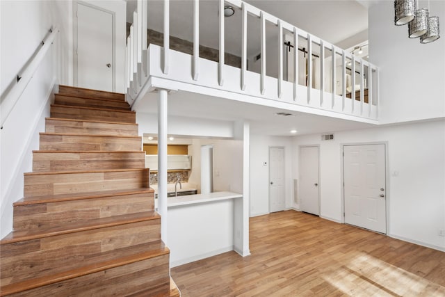 stairway featuring a high ceiling and hardwood / wood-style floors