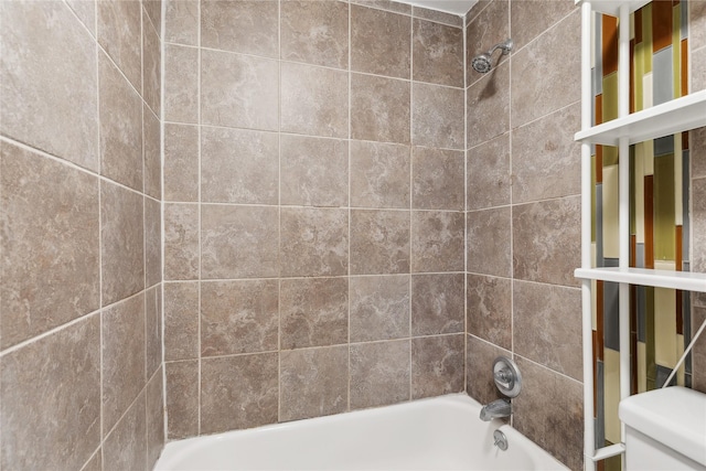 bathroom with tiled shower / bath combo and toilet