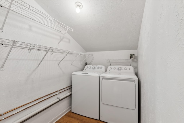 washroom featuring washing machine and dryer, hardwood / wood-style floors, and a textured ceiling