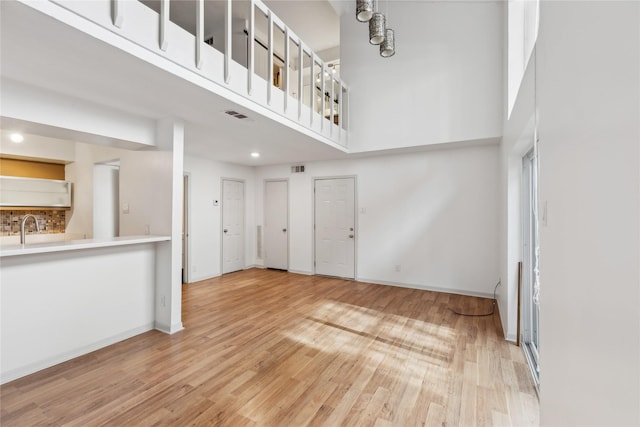 unfurnished living room featuring hardwood / wood-style floors, a towering ceiling, and sink