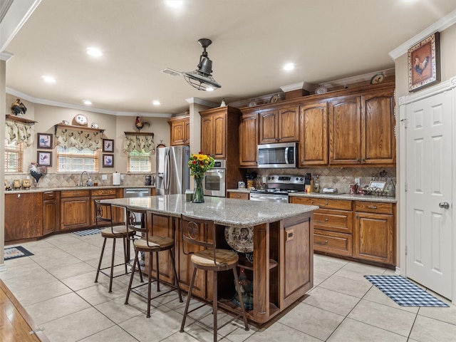 kitchen with light tile patterned floors, a breakfast bar, appliances with stainless steel finishes, backsplash, and a kitchen island