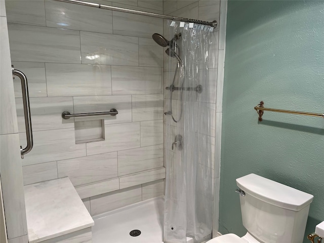 full bathroom with a textured wall, a shower stall, and toilet