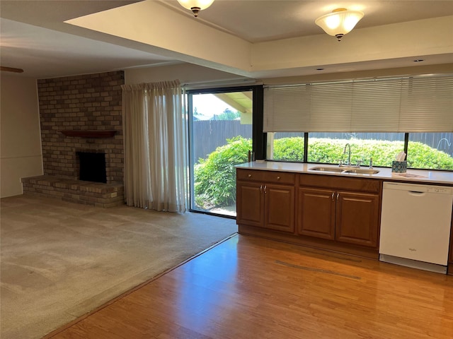 2118 Courtland Cir, Carrollton, TX 75007 - kitchen with dishwasher, a sink, light wood finished floors, a brick fireplace, and open floor plan