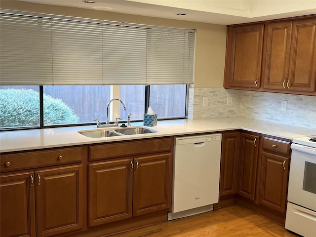 kitchen with light countertops, white appliances, light wood-type flooring, and a sink