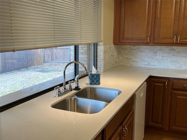 kitchen featuring dishwasher, tasteful backsplash, light countertops, and a sink