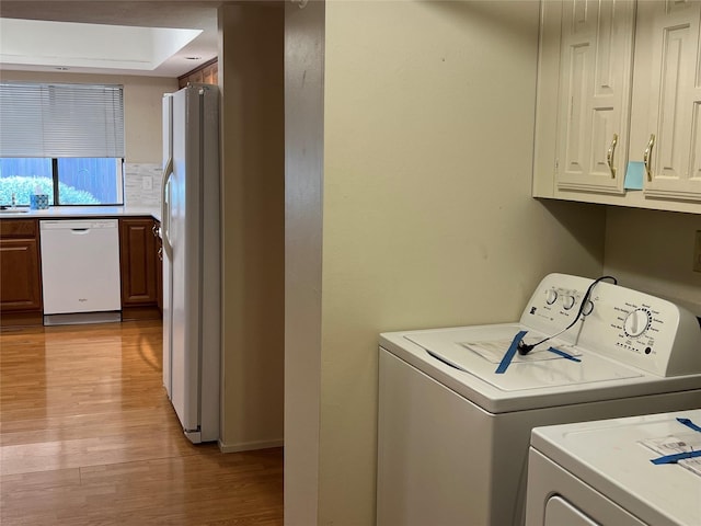 laundry area featuring light wood finished floors, washer and clothes dryer, and cabinet space