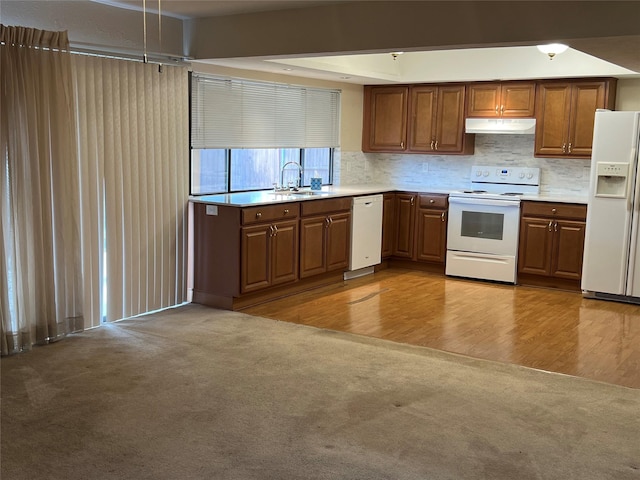 kitchen featuring light countertops, light carpet, a sink, white appliances, and under cabinet range hood