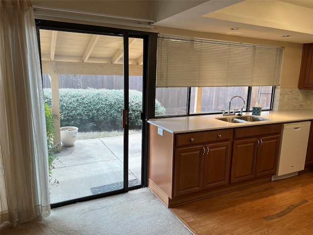 kitchen with light countertops, dishwasher, backsplash, and a sink