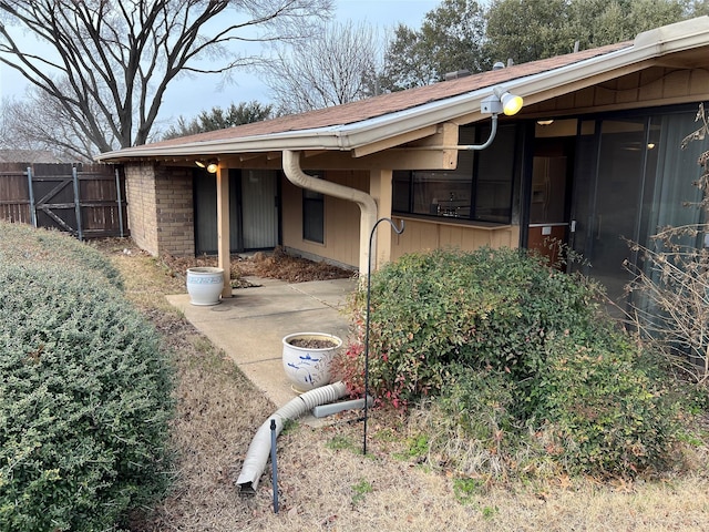 view of side of property with brick siding and fence