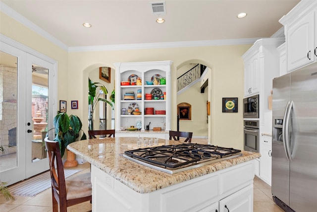 kitchen featuring white cabinetry, a kitchen island, stainless steel appliances, light stone countertops, and a kitchen bar