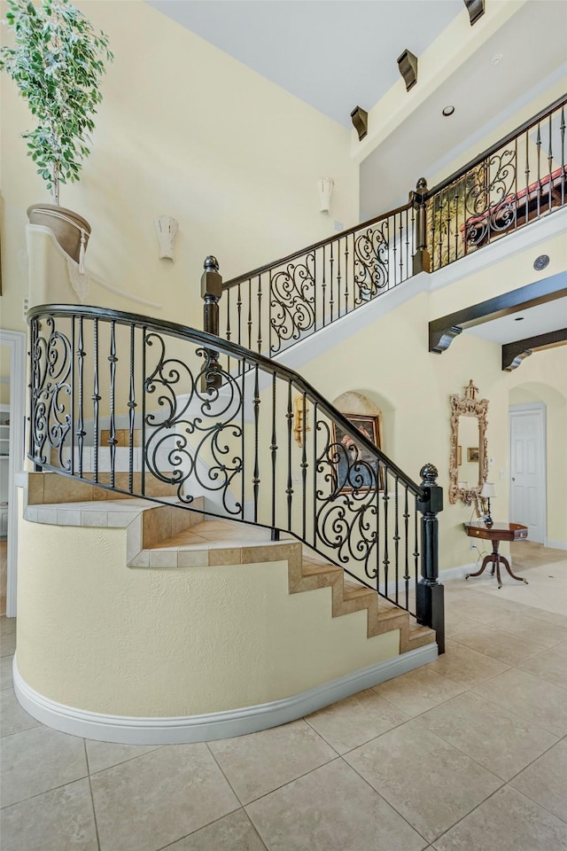 stairs featuring tile patterned floors and a high ceiling