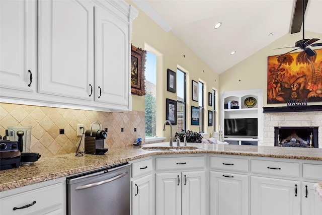 kitchen featuring sink, lofted ceiling with beams, stainless steel dishwasher, ceiling fan, and white cabinets