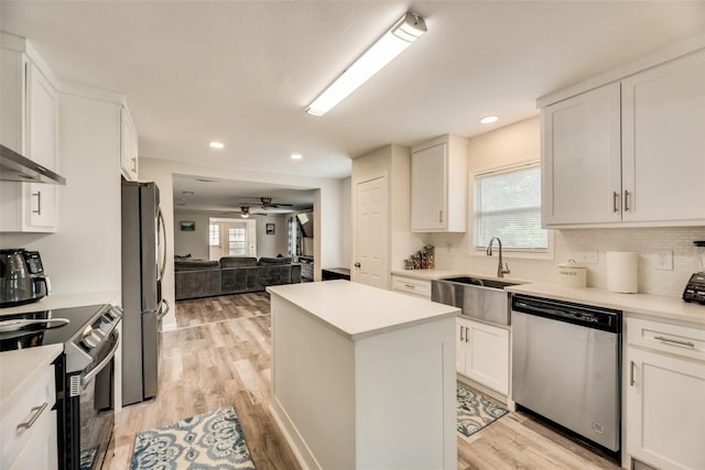 kitchen with stainless steel appliances, a center island, white cabinets, and light wood-type flooring