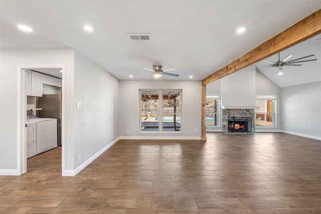 unfurnished living room with a healthy amount of sunlight, washer and dryer, vaulted ceiling with beams, and dark hardwood / wood-style floors