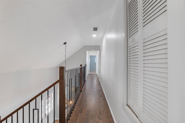 hallway with lofted ceiling, dark hardwood / wood-style floors, and a textured ceiling