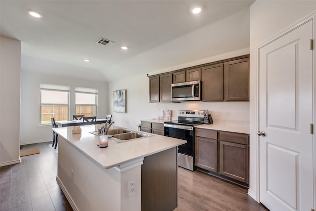 kitchen featuring hardwood / wood-style flooring, appliances with stainless steel finishes, sink, and an island with sink