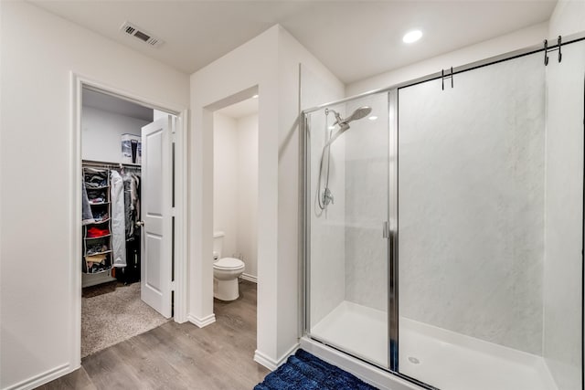 bathroom with wood-type flooring, an enclosed shower, and toilet